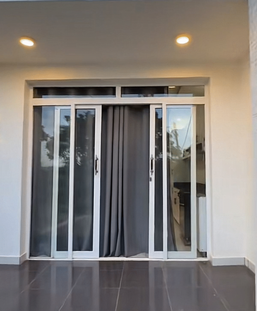 Pintu sliding UPVC putih modern terpasang di ruang tamu minimalis